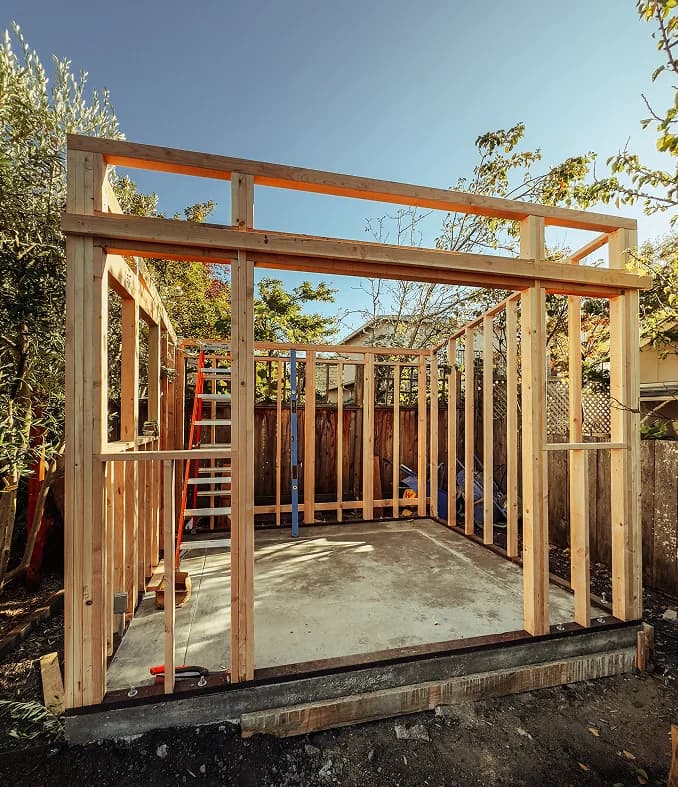 The frame standing on its concrete slab, studs and headers still open to the sky