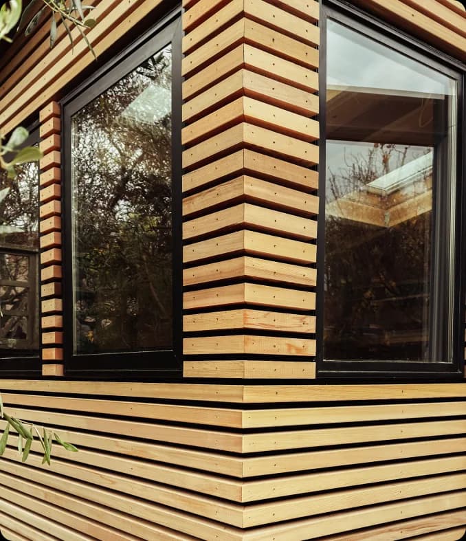 A corner of the finished building, where the cedar slats are mitred to turn the corner beside a window